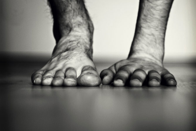 Fekete-fehér kép egy szőrös lábfej és egy tenyér egymás mellett.