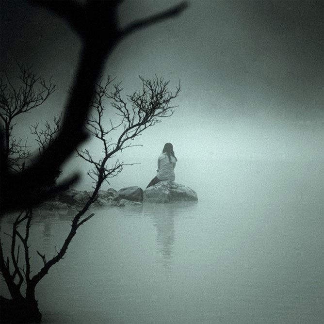Vízparton magányosan ülő nő.