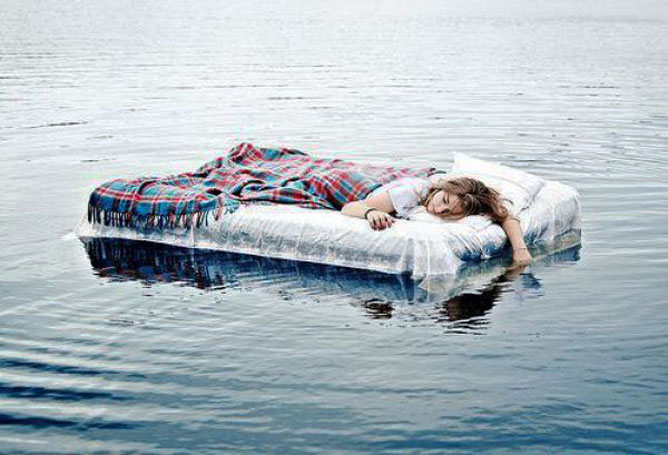 Egy ágyon alvó nő a víz közepén.