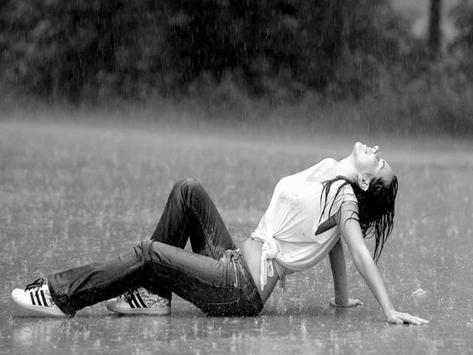 Fiatal lány az esőben egy réten.