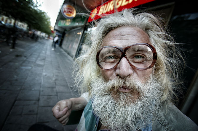 Hajléktalan szemüveges ember érdeklődő tekintettel.