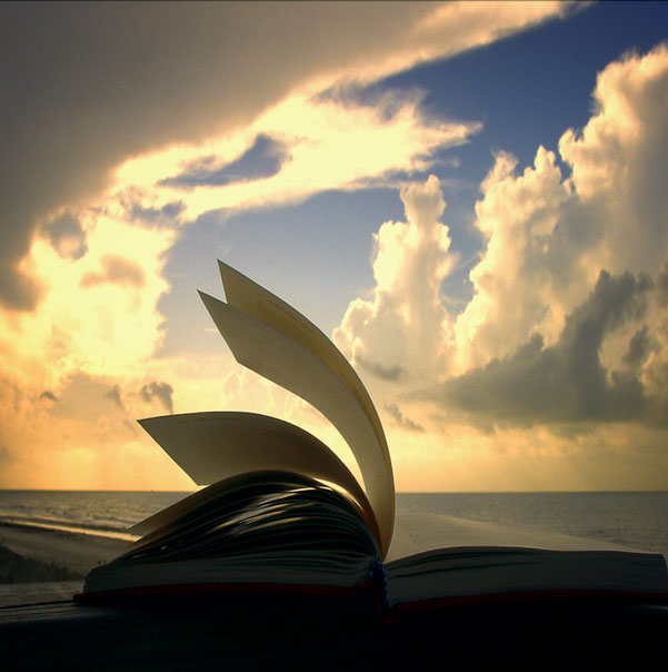 Egy nyitott könyv a felhős ég alatt.