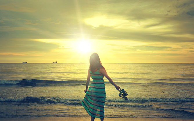 Lány a tengerparti naplementében.